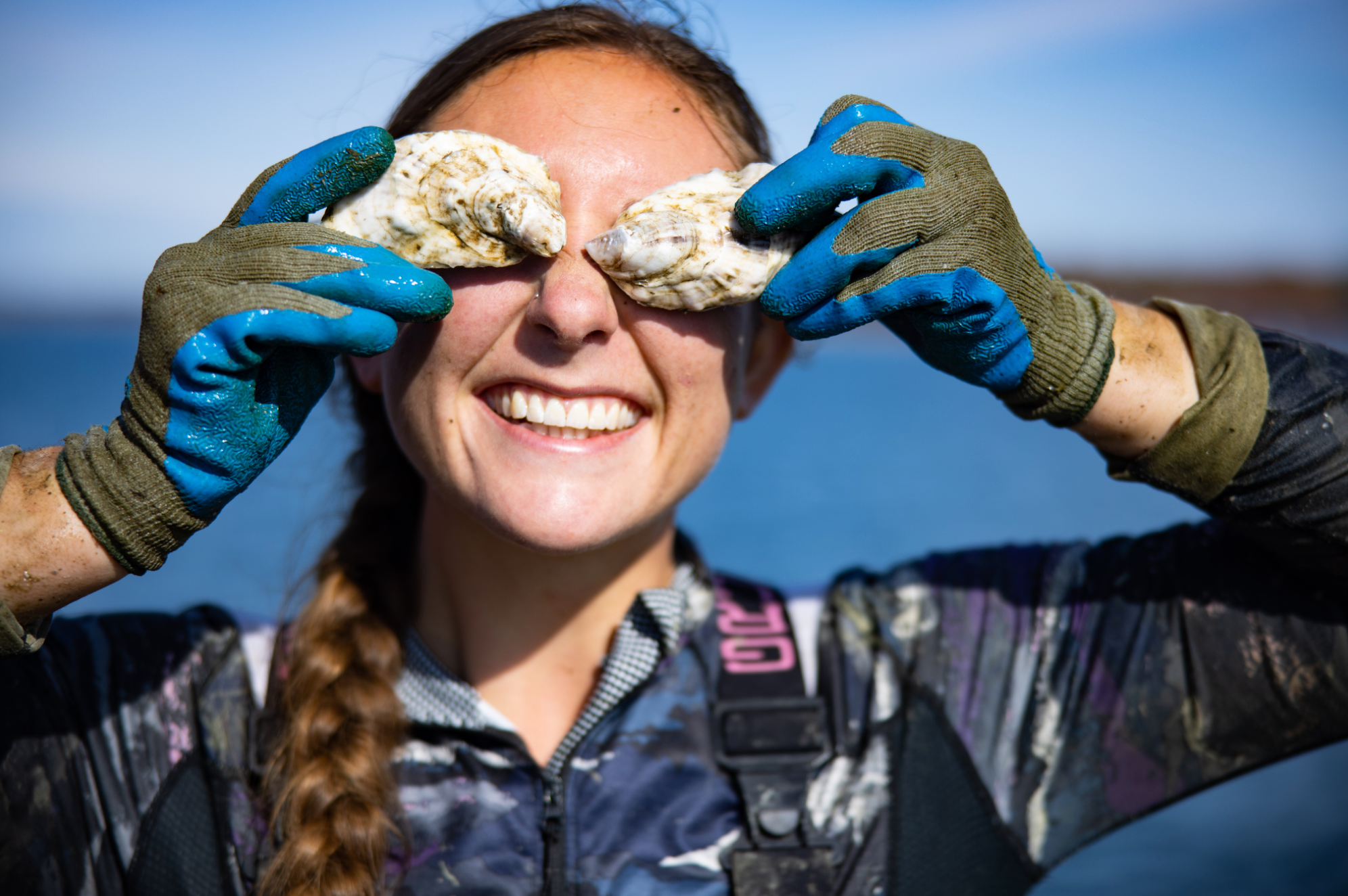 A woman smiling holding oyster shell on her face. 